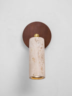 Front view of the Clérachic travertine spotlight pointing straight down from a round walnut wall plate on a white wall.