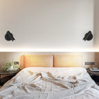 Two black Clérachic spotlight wall lights flank a bed, shown in a close crop on a pale wall above and in a full bedroom view below.