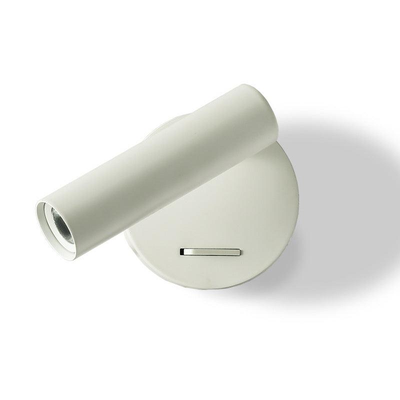 A white Clérachic spotlight wall light, its cylinder head swung out sideways from a round white backplate with a slide switch, on white.