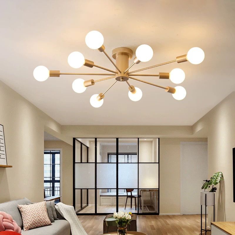 This gold Clérachic Sputnik Globe Ceiling Light lights a living room with a glass room divider and a patterned sofa.
