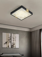 Clérachic Square Alabaster Flush Mount Ceiling Light lit in a bedroom beside a pair of framed ink paintings, warm stone face against grey walls.