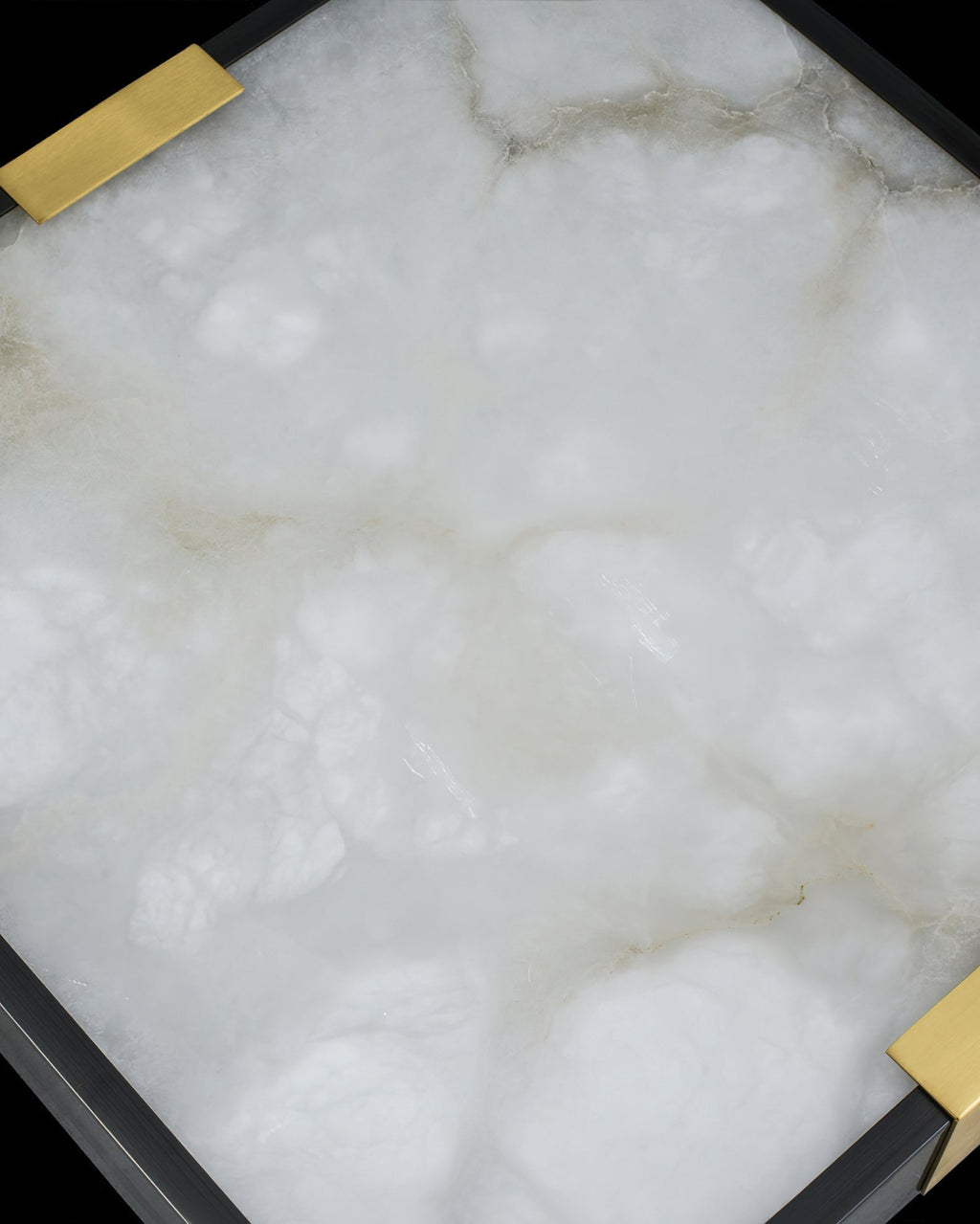 Macro of the Clérachic Square Alabaster Flush Mount Ceiling Light panel, cloudy white alabaster with amber veins running between the brass saddles.