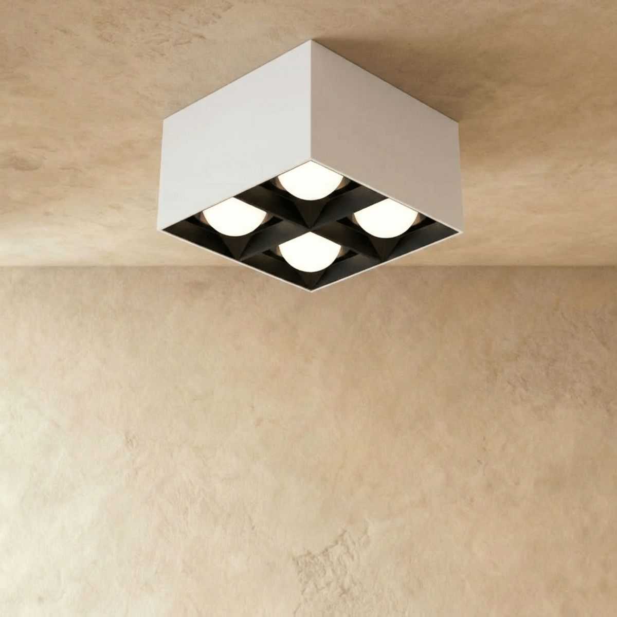 Clérachic white square box ceiling downlight with four round lit spot cells and black reflectors, shown in the studio on limewash.