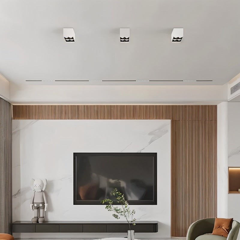 Clérachic row of three white square box downlights across a living room ceiling above a wood-slat and marble TV wall.