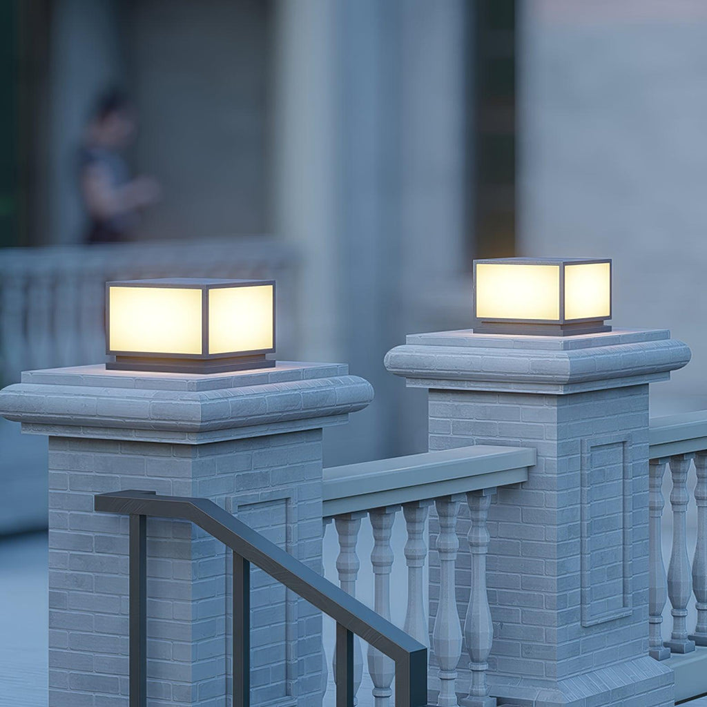 Warm-glowing Clérachic post lights on pale brick pillars with a white balustrade between them, in the blue light of evening.