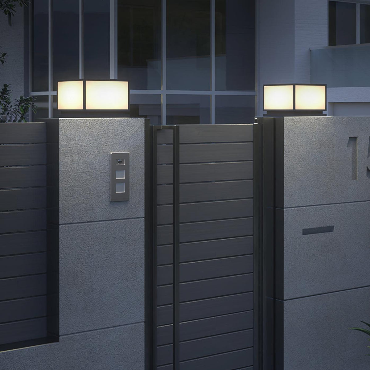 Lit square Clérachic post lights on grey pillars beside a horizontal-slatted gate, with a modern building behind.
