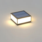 Solar version of this Clérachic square post light, shown from above with its blue solar panel and a warm glow around the base.