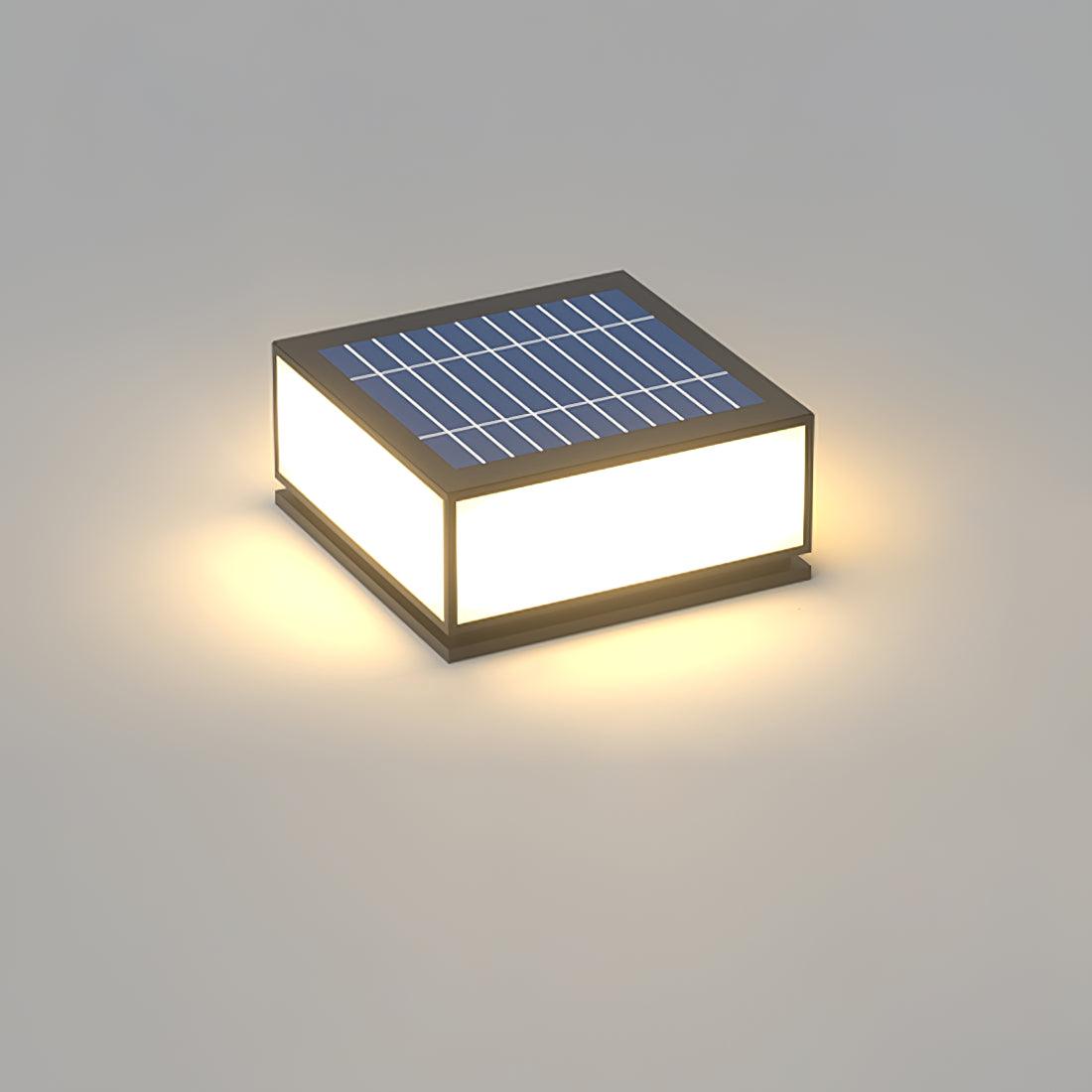 Solar version of this Clérachic square post light, shown from above with its blue solar panel and a warm glow around the base.