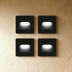 Clérachic recessed stair lights in black, four units in a two-by-two grid on plaster, each lit cool white.