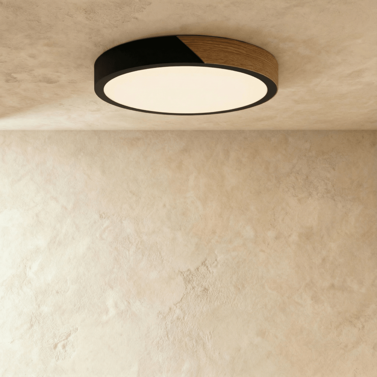 Clérachic round flush ceiling light in black and wood, glowing softly against a textured plaster ceiling above a bare wall.