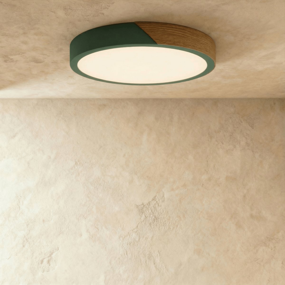 Clérachic round flush ceiling light in deep green and wood, lit warm, with the glow washing across the plaster around it.