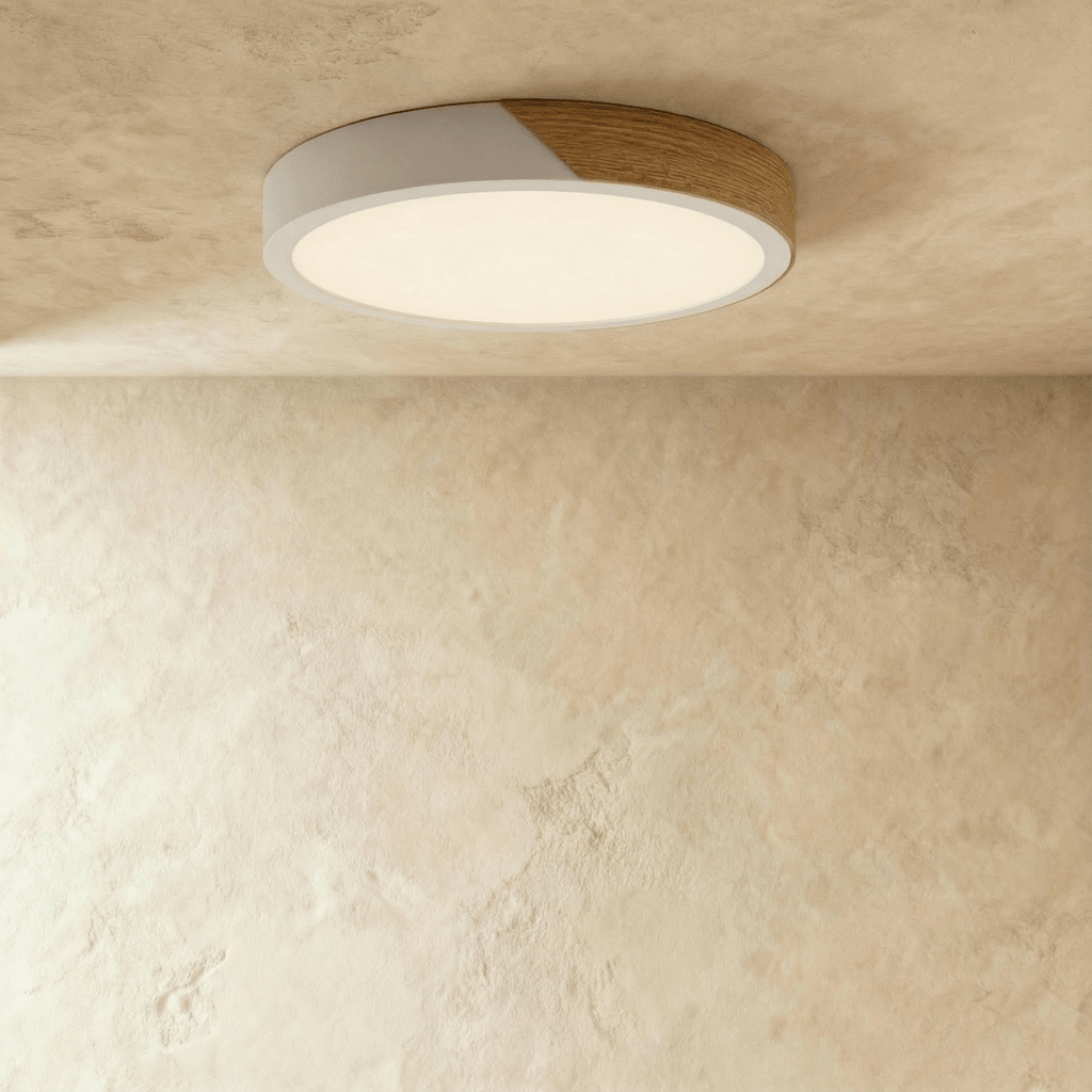Clérachic round flush ceiling light in white and wood, lit warm so the pale rim almost disappears into the plaster ceiling.