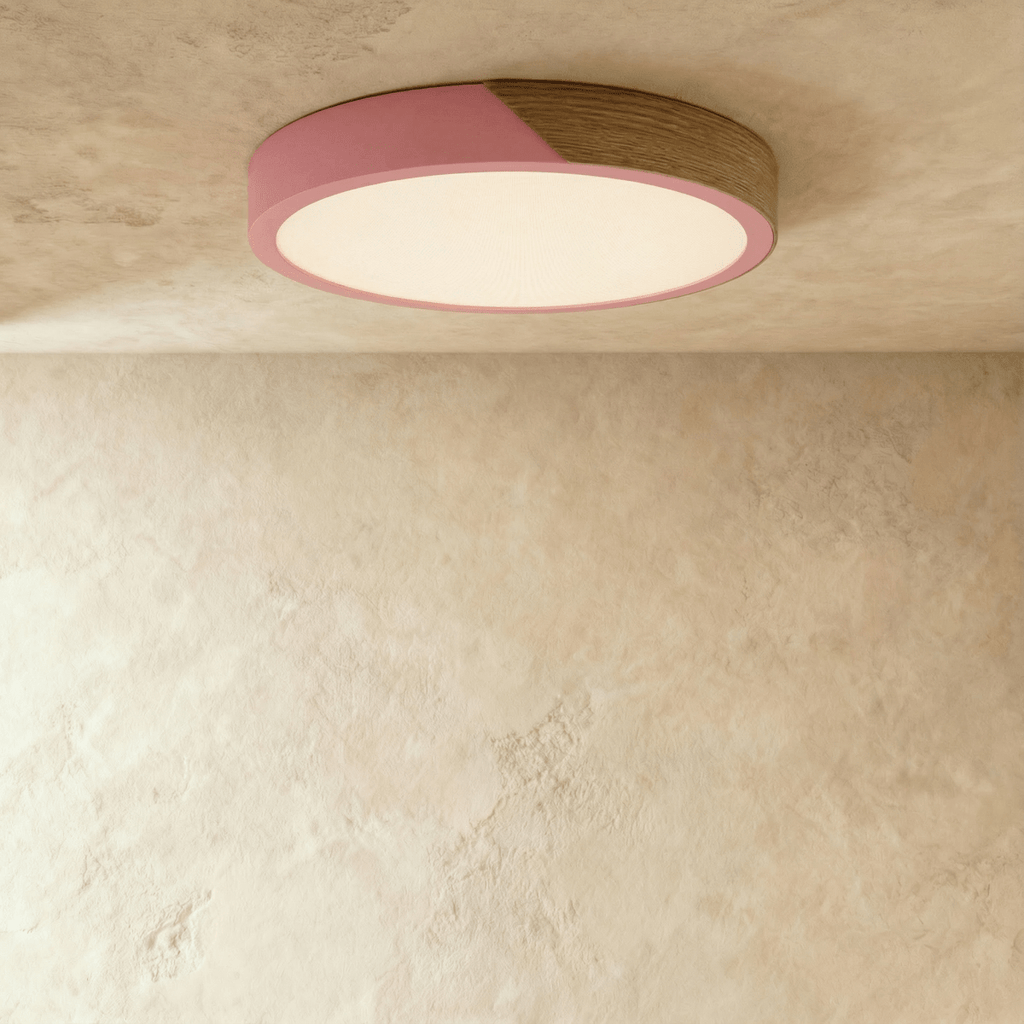 Clérachic round flush ceiling light in dusty pink and wood, its diffuser lit warm beneath the two-tone band.
