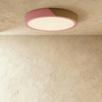 Clérachic round flush ceiling light in dusty pink and wood, its diffuser lit warm beneath the two-tone band.