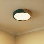 Clérachic round flush ceiling light in deep green and wood, glowing bright white in the corner of a softly lit room.