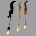 Three Clérachic squirrel and pinecone pendant lights in black, white and tan resin, each holding an exposed Edison bulb.