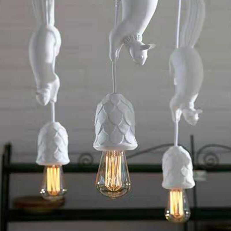 Close-up of three white Clérachic squirrel pendant lights, showing the pinecone-textured resin cups around each bulb.
