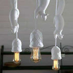 Close-up of three white Clérachic squirrel pendant lights, showing the pinecone-textured resin cups around each bulb.