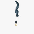 Studio shot of a single dark blue Clérachic squirrel and pinecone pendant light with an exposed filament bulb below.