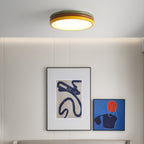 Small in the frame, this Clérachic ceiling light glows above a wall with two abstract blue prints and a long ledge.