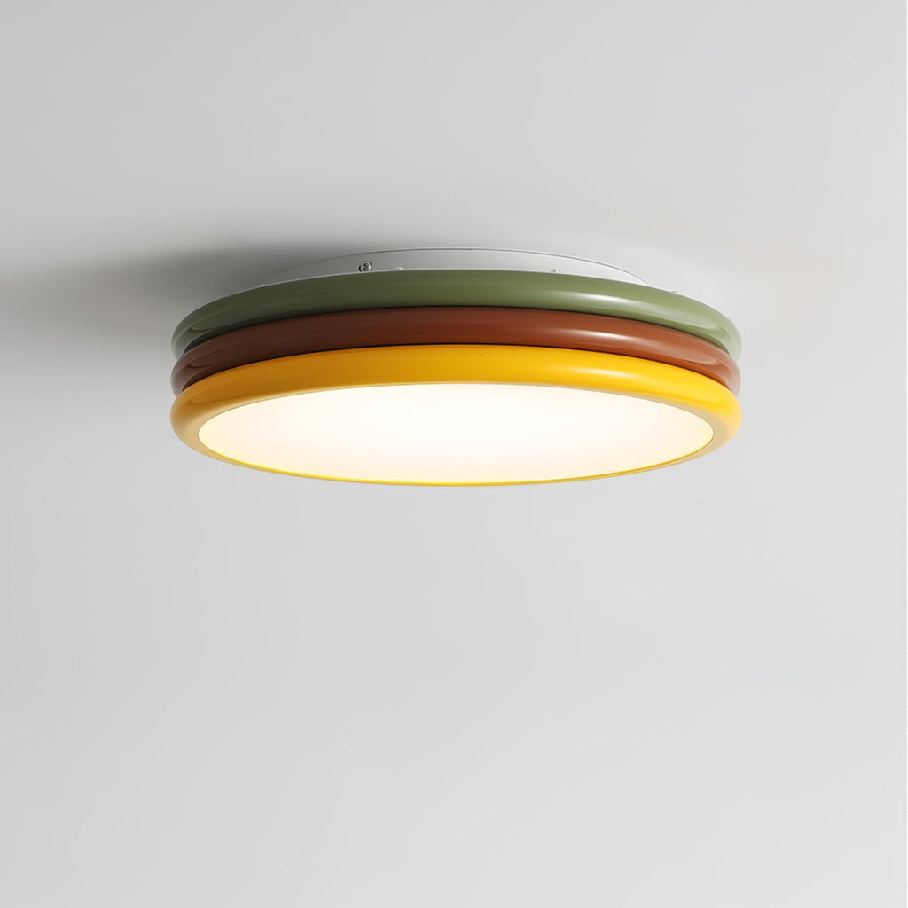 Clérachic ceiling light seen from below at an angle, its green, red-brown and yellow rings around a softly glowing diffuser.