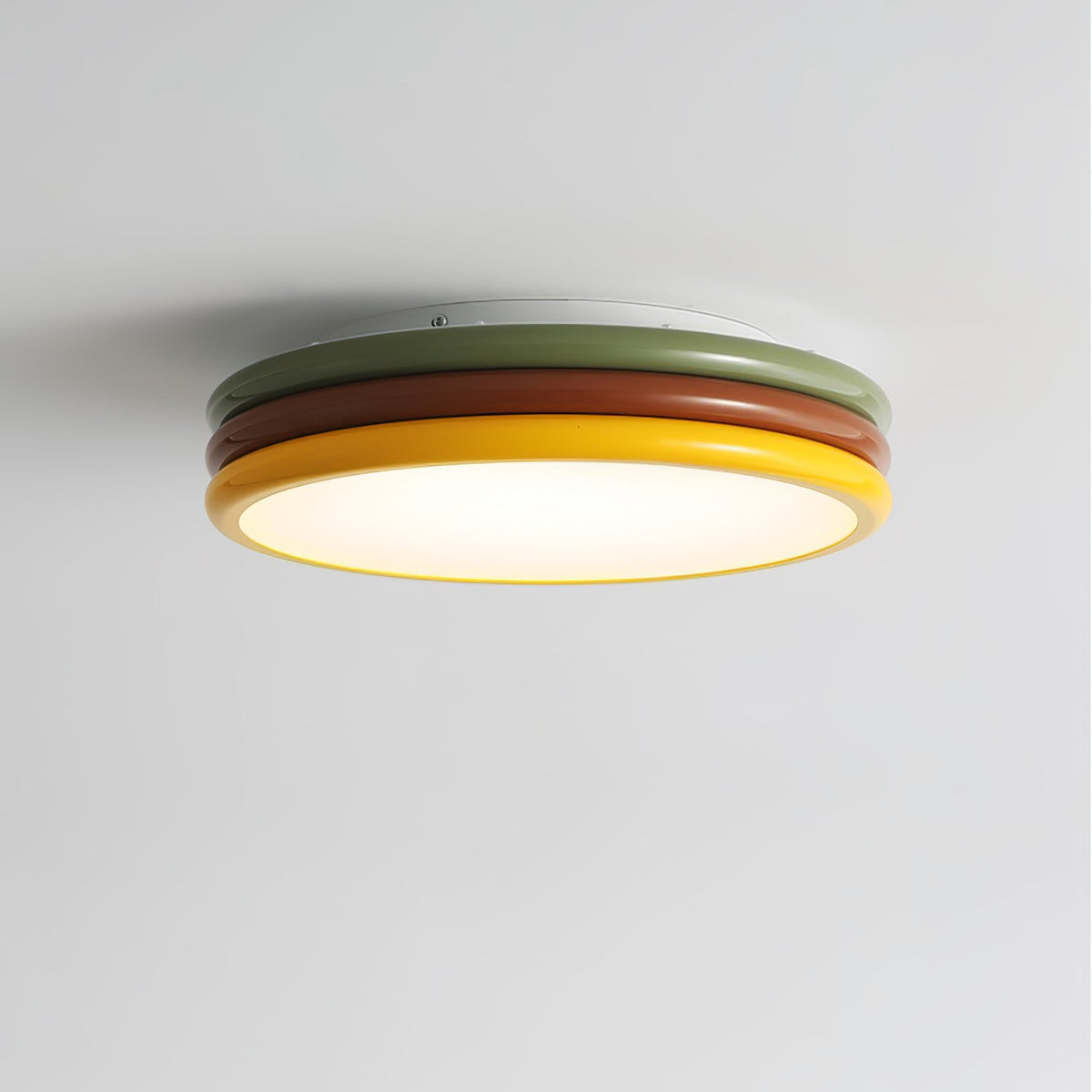 Clérachic ceiling light seen from below at an angle, its green, red-brown and yellow rings around a softly glowing diffuser.