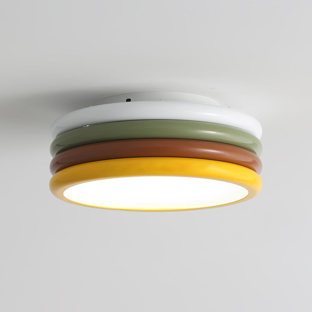 Low close-up of this Clérachic ceiling light, its white canopy ring above the green and red-brown tiers and a yellow rim.