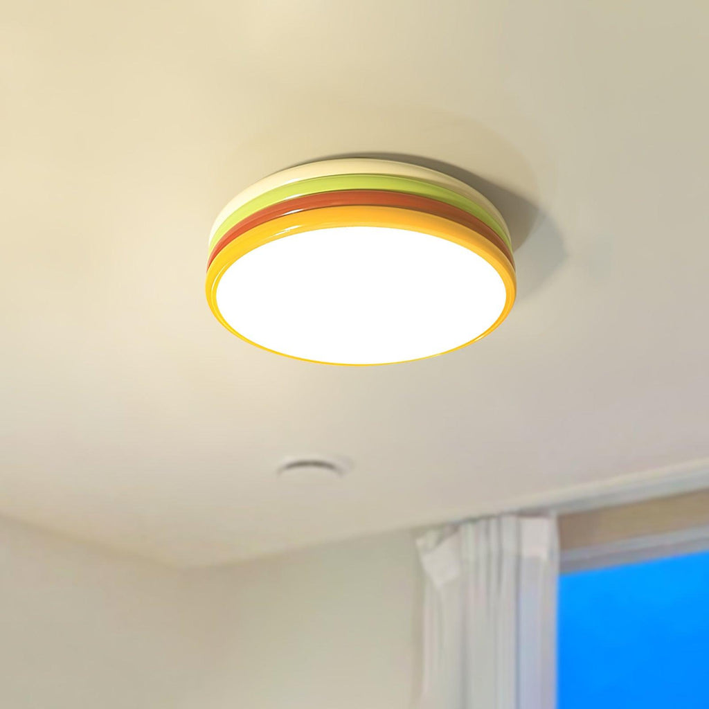 Clérachic ceiling light in lime green and orange-red, lit warmly on a cream ceiling near a small vent and a blue window.