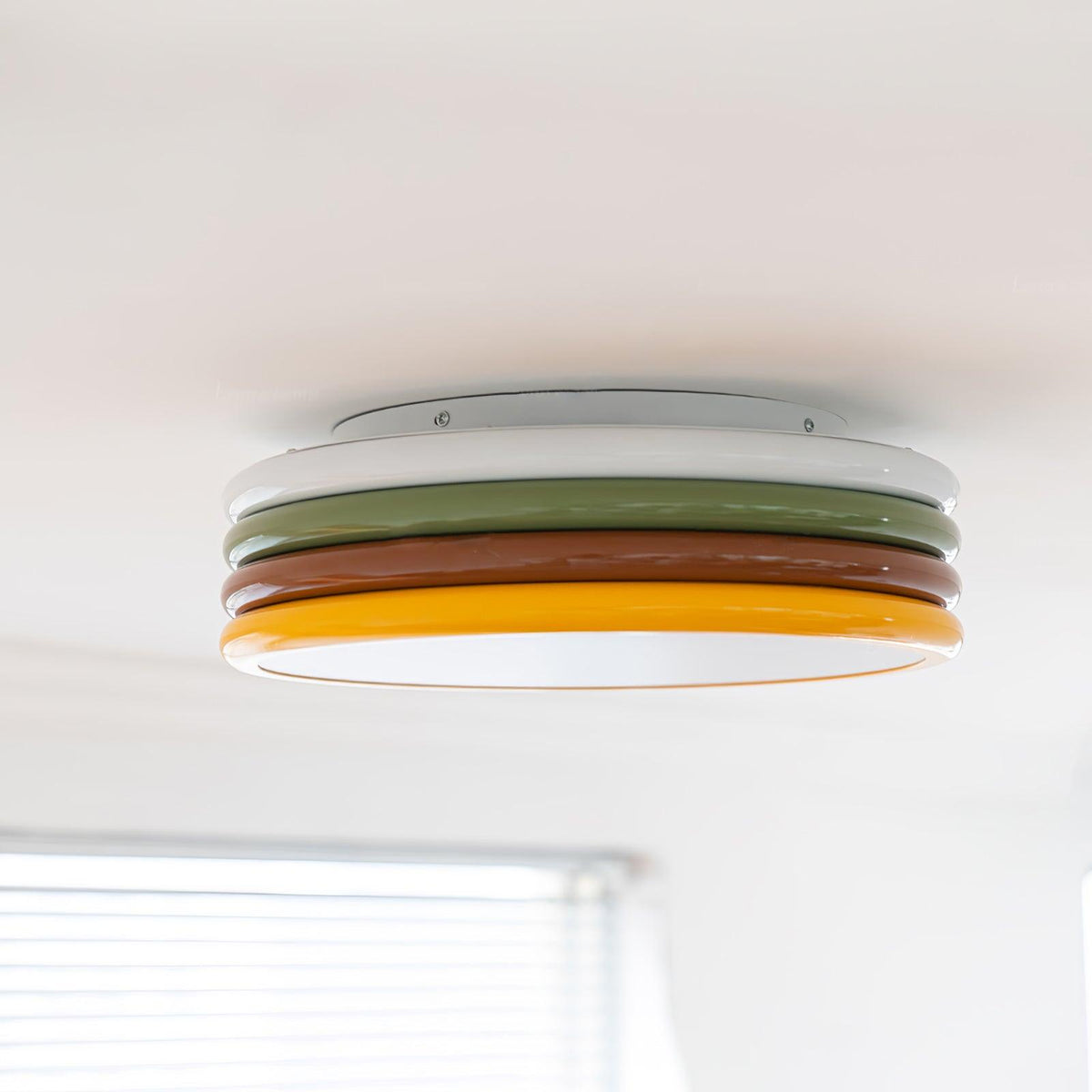 Wide view of this Clérachic ceiling light with its four stacked rings, above a window blind in a bright white room.