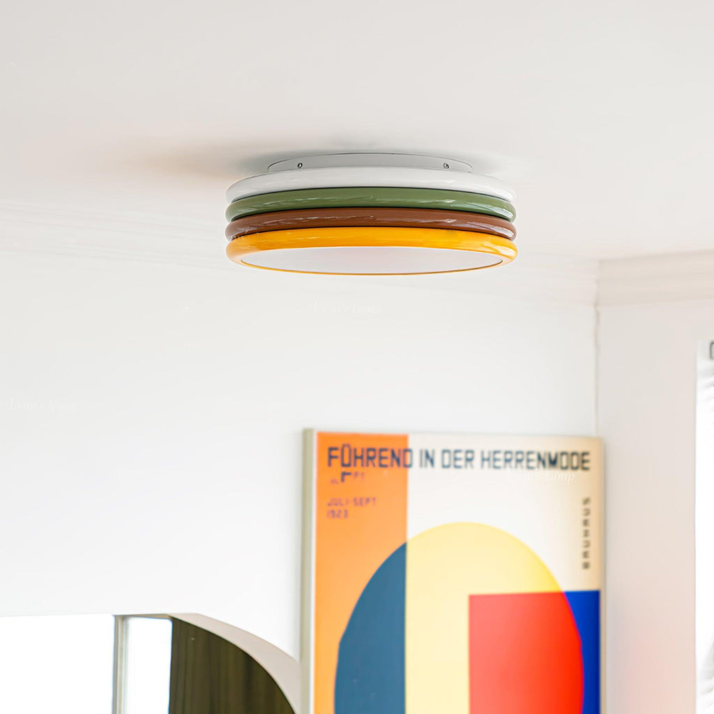 Clérachic ceiling light with its white, green, red-brown and yellow tiers, above a large geometric poster in a white room.