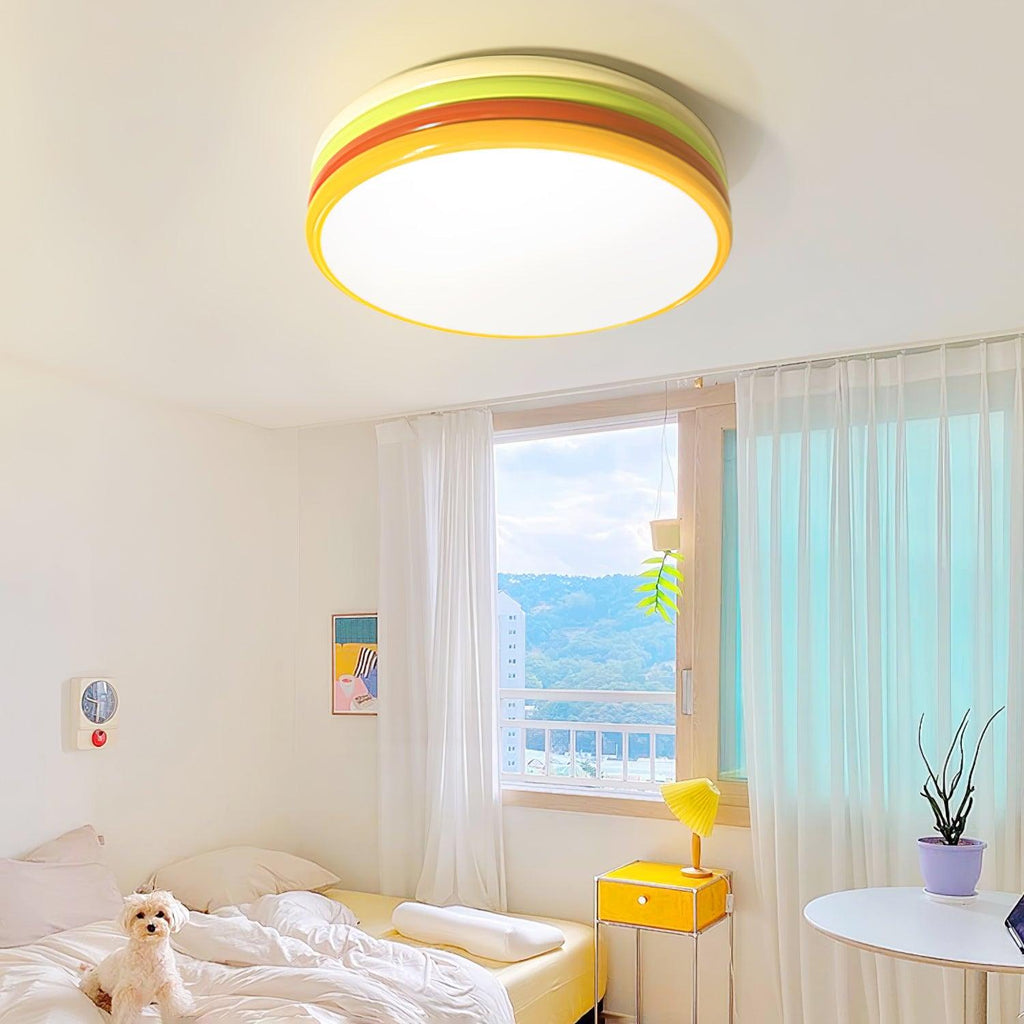Close view of a lit Clérachic ceiling light in a bright bedroom, with a sheer curtain, a yellow nightstand and a potted plant.