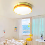 Close view of a lit Clérachic ceiling light in a bright bedroom, with a sheer curtain, a yellow nightstand and a potted plant.