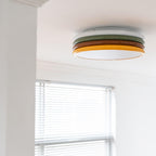 Clérachic ceiling light mounted beside a white boxed beam, with a window blind in the lower half of the frame.