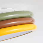 Close view of the green, red-brown and yellow rings on this Clérachic ceiling light, with the diffuser edge at the bottom.