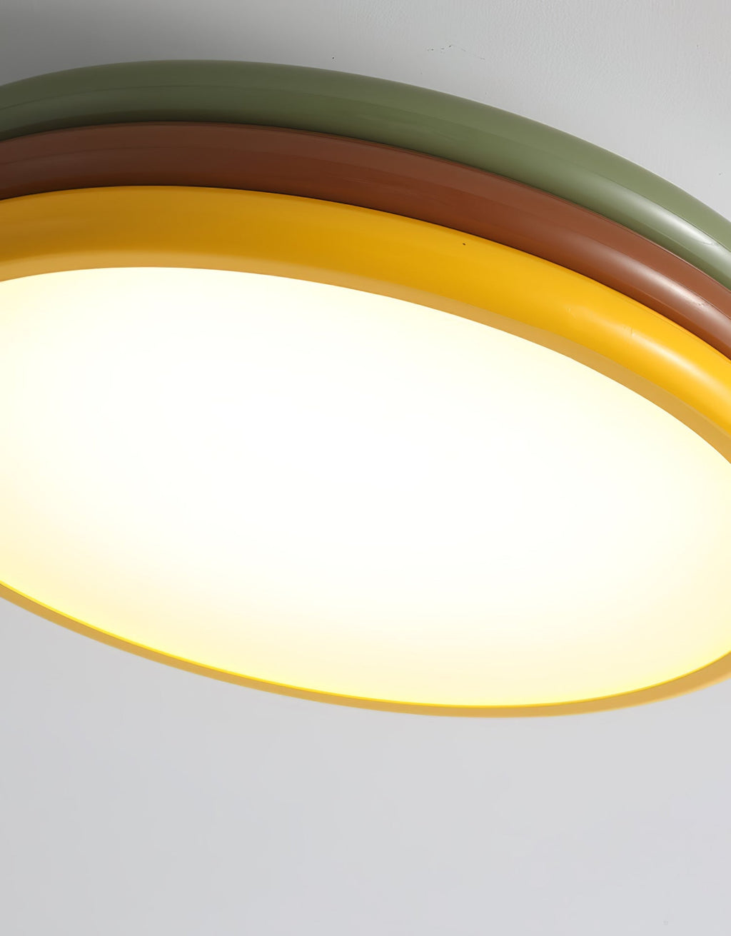 Close view of the glowing diffuser and yellow outer ring of this Clérachic ceiling light, with green and red-brown tiers above.