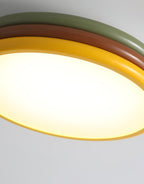 Close view of the glowing diffuser and yellow outer ring of this Clérachic ceiling light, with green and red-brown tiers above.