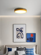 Clérachic ceiling light above a headboard wall with two abstract prints and blue and white patterned cushions on the bed.