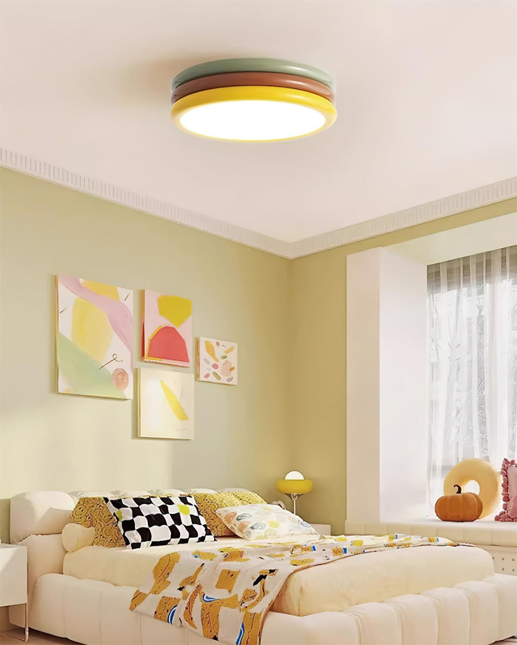 Lit Clérachic ceiling light in a pale green bedroom with colourful wall prints, a checked cushion and a pumpkin on the sill.