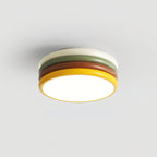 Lit Clérachic ceiling light on a plain grey background, its cream top ring, green, red-brown and yellow tiers all visible.