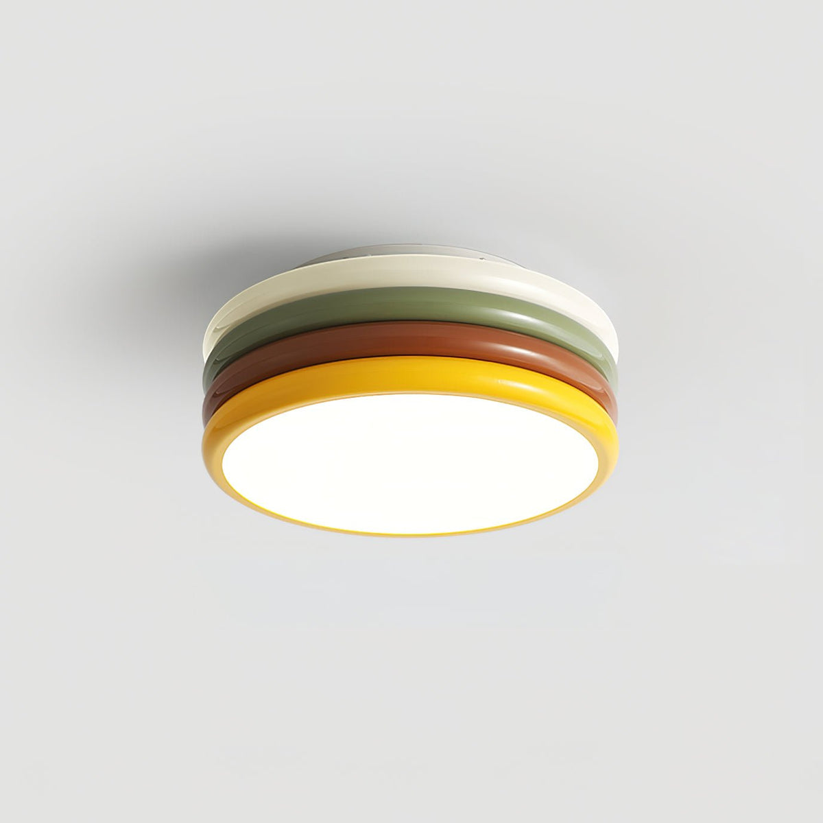 Lit Clérachic ceiling light on a plain grey background, its cream top ring, green, red-brown and yellow tiers all visible.