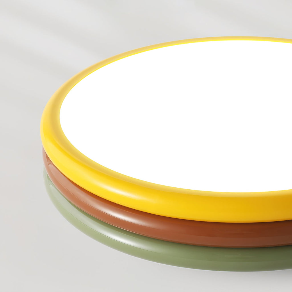 Close view of this Clérachic ceiling light's yellow rim, red-brown and green tiers, with the lit diffuser filling the top.