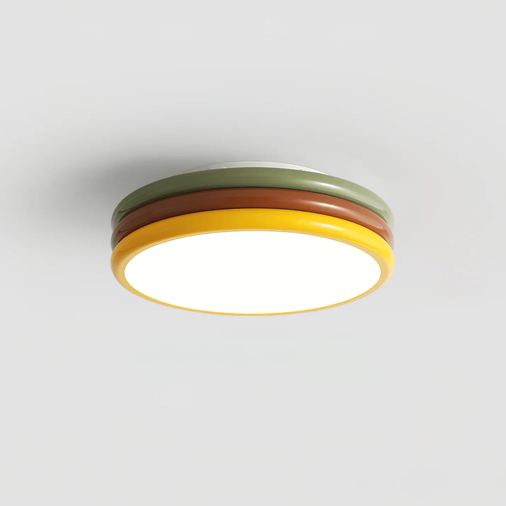 Clérachic ceiling light lit on a grey backdrop, with the red-brown and green rings rising above a warm glowing base.