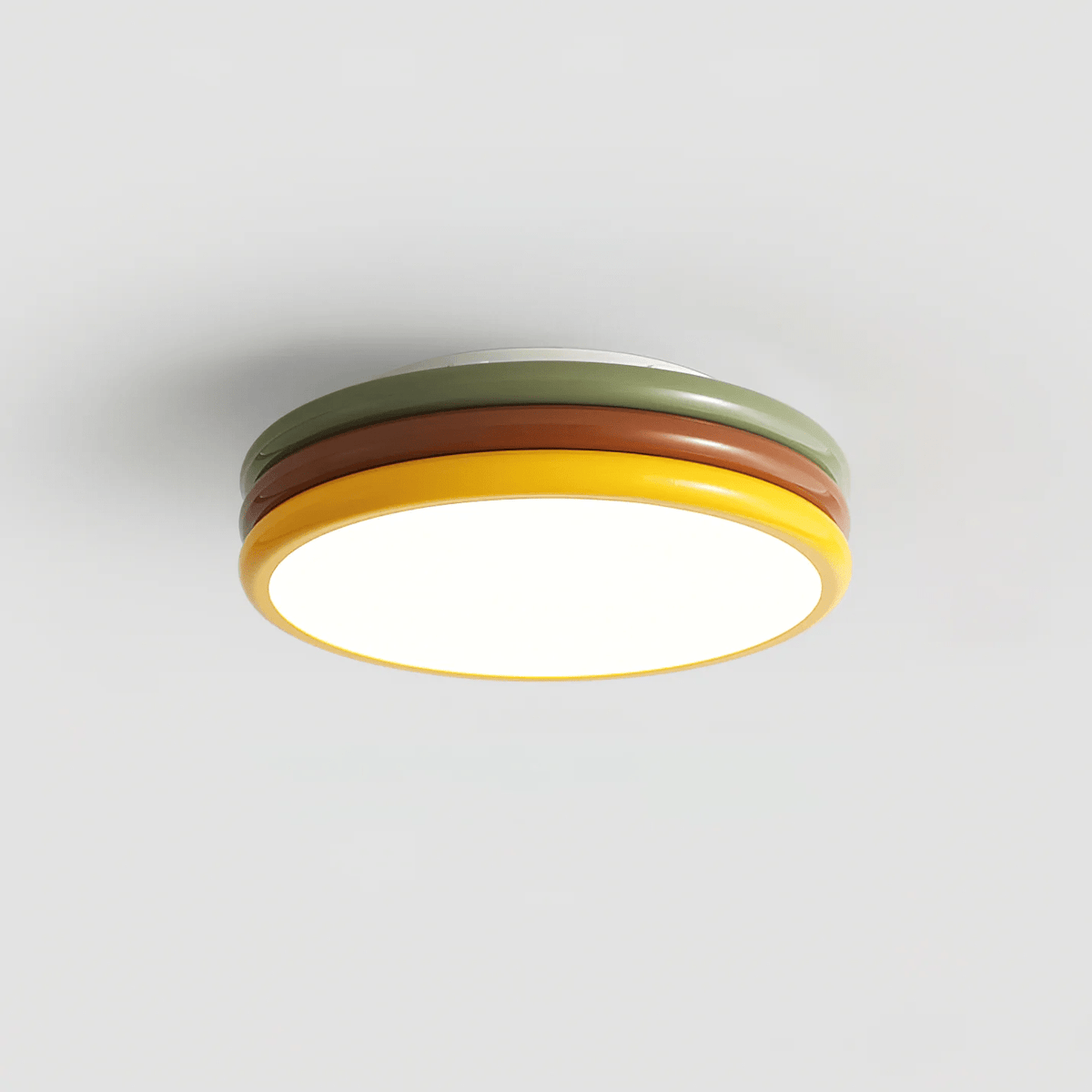 Clérachic ceiling light lit on a grey backdrop, with the red-brown and green rings rising above a warm glowing base.