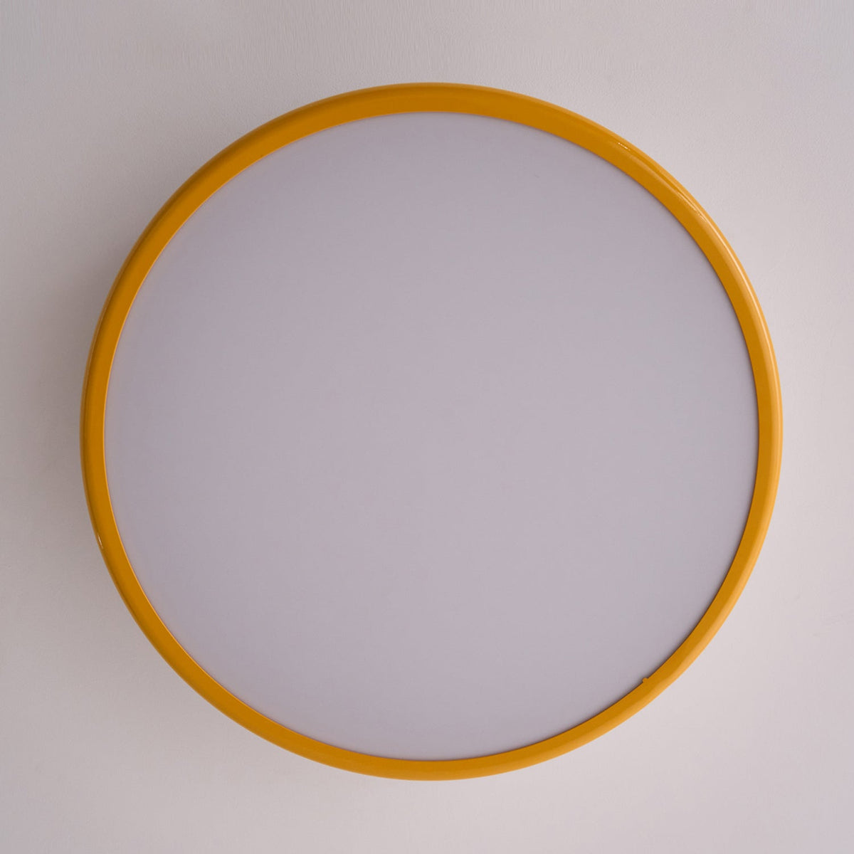 Looking straight up at the unlit frosted diffuser and golden-yellow outer ring of this Clérachic ceiling light.