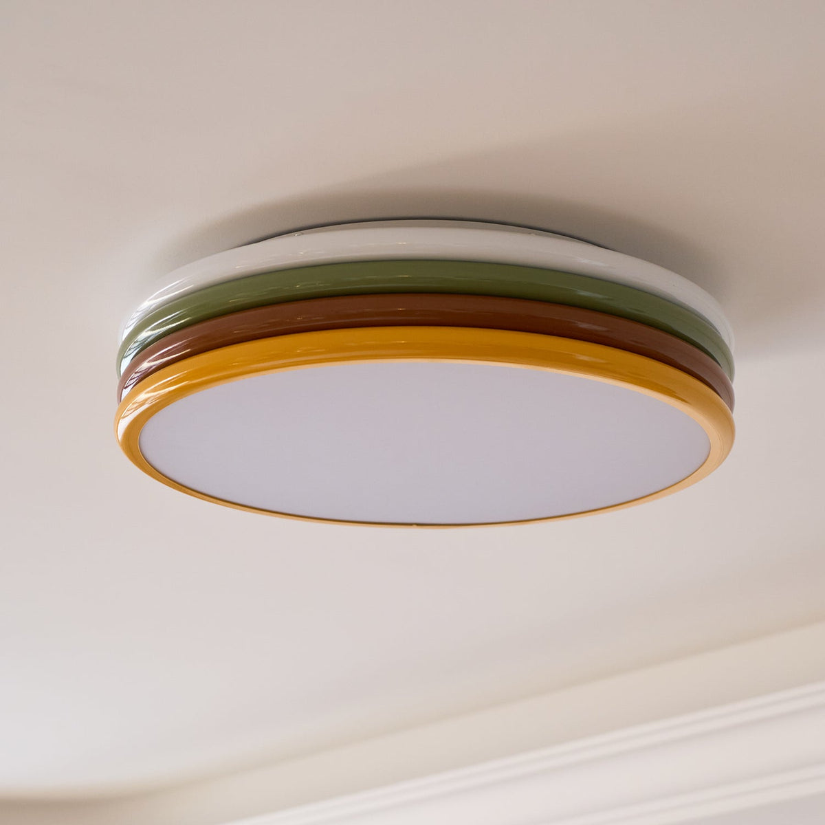 Clérachic ceiling light seen from below, unlit, with a pale curved cornice running along the cream ceiling beside it.