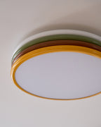 Cropped view of the unlit Clérachic ceiling light, its four coloured tiers curving over a frosted diffuser on a taupe ceiling.