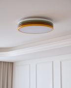 Unlit Clérachic ceiling light on a pale ceiling, with a stepped cornice and white wall panels below it.