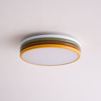 Unlit Clérachic ceiling light on a soft pink-white ceiling, its frosted diffuser and four coloured tiers seen from the side.