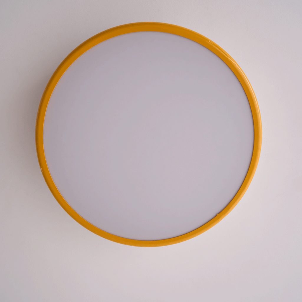 Looking up at the unlit round diffuser, framed by a golden-yellow ring, on this Clérachic ceiling light.