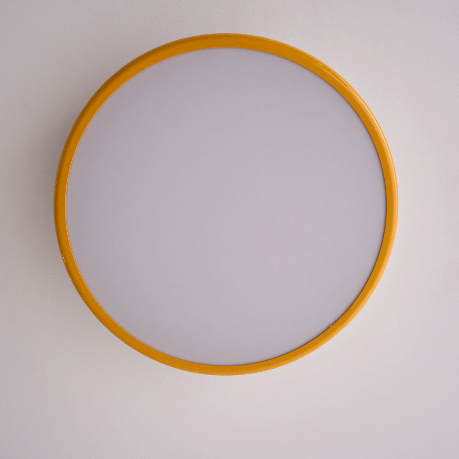 Looking up at the unlit round diffuser, framed by a golden-yellow ring, on this Clérachic ceiling light.